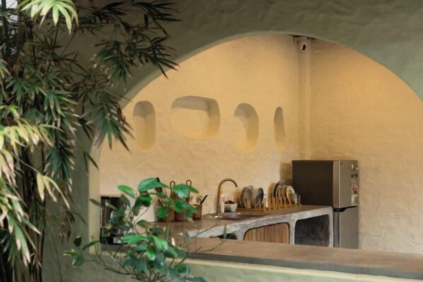 Una cocina con techo abovedado, un refrigerador y un lavamanos.