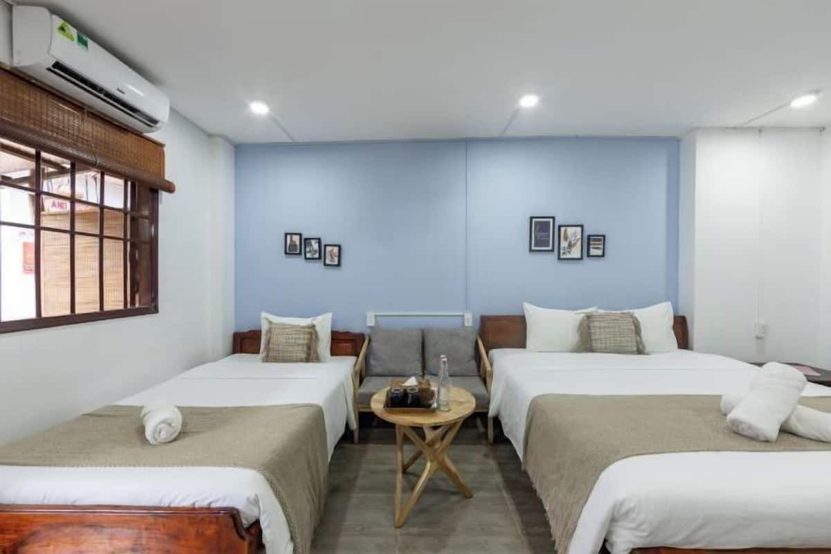 A hotel room with two beds, a small round table, and an air conditioning unit.