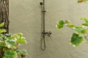 A showerhead mounted on a wall with a visible water spout and a handheld shower attachment. - Canaan Beach Home (Phu Quoc Island)