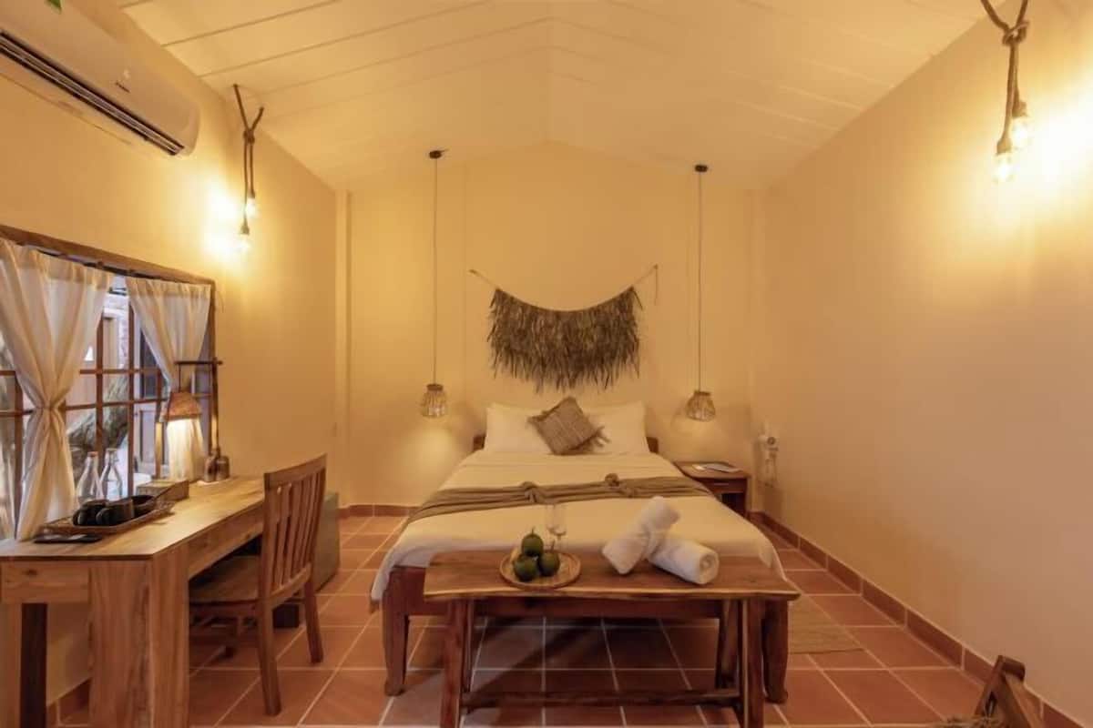 A room with a bed, bedside table, lamp, and a hanging decoration.
