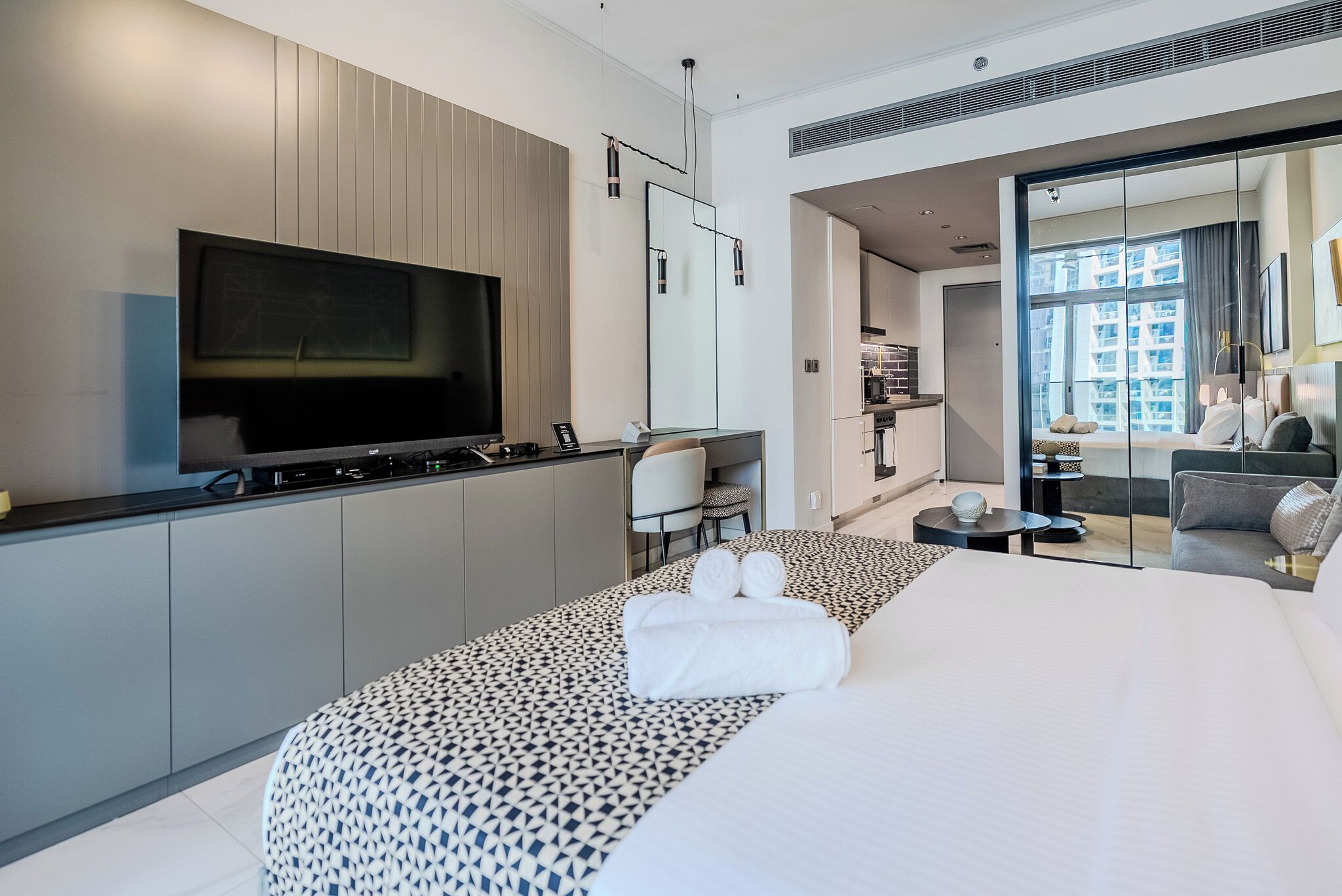 Une chambre d’hôtel moderne dotée d’un grand lit, d’une télévision à écran plat, d’un bureau et d’un coin salon offrant une vue sur la ville.