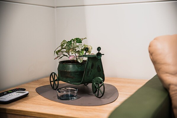 Um pequeno cachepot verde com uma planta sobre uma mesa de madeira.