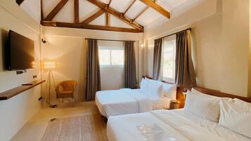 Quarto de hotel com teto de madeira, duas camas, uma TV, uma cadeira e um tapete.