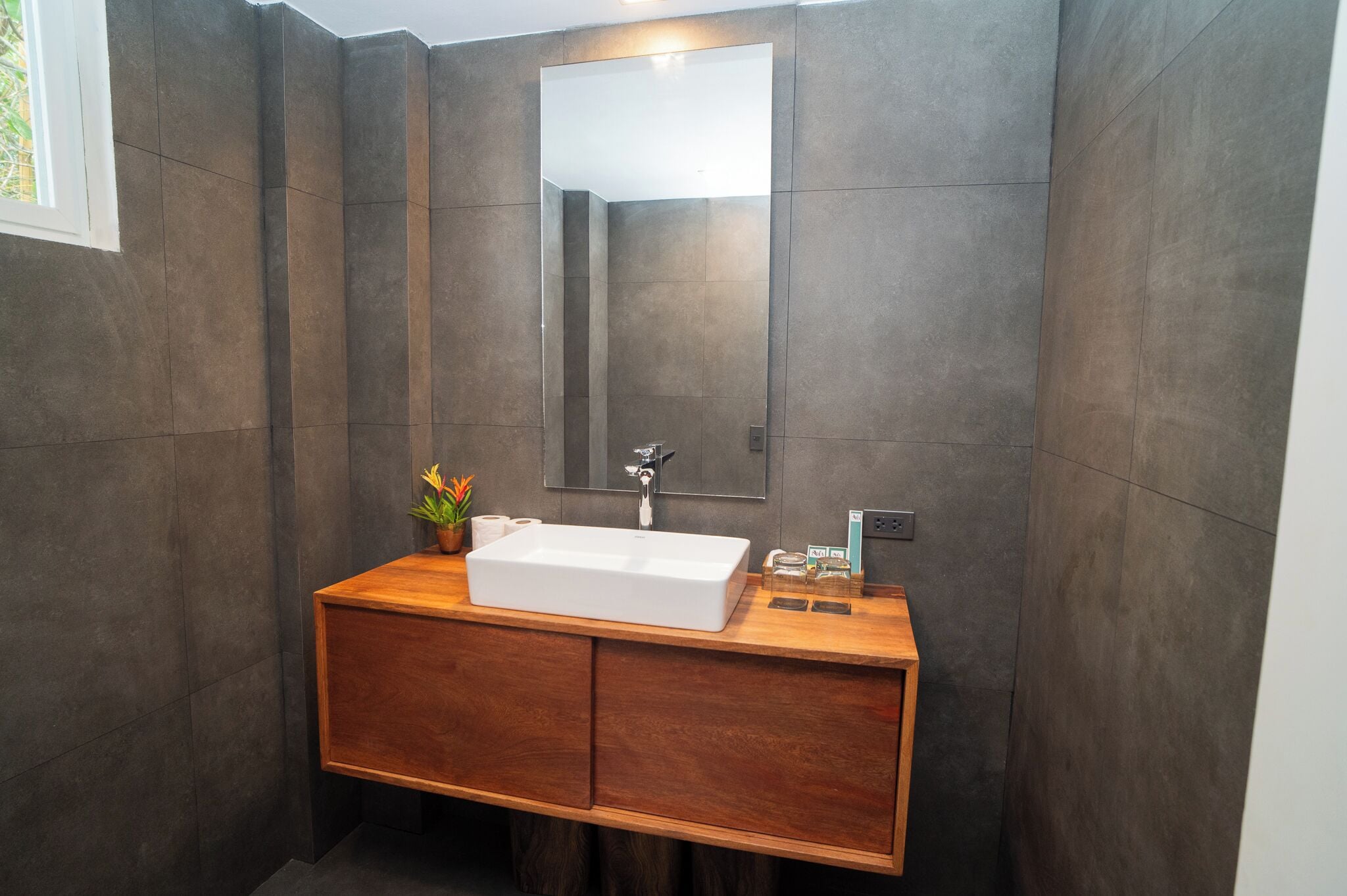 A modern bathroom with a wooden vanity, a large mirror, and a white sink.
