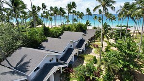 Ein Resort mit mehreren Gebäuden, einem Strand und Palmen.