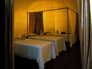 Une chambre avec quatre lits alignés, chacun étant surmonté d’un baldaquin.