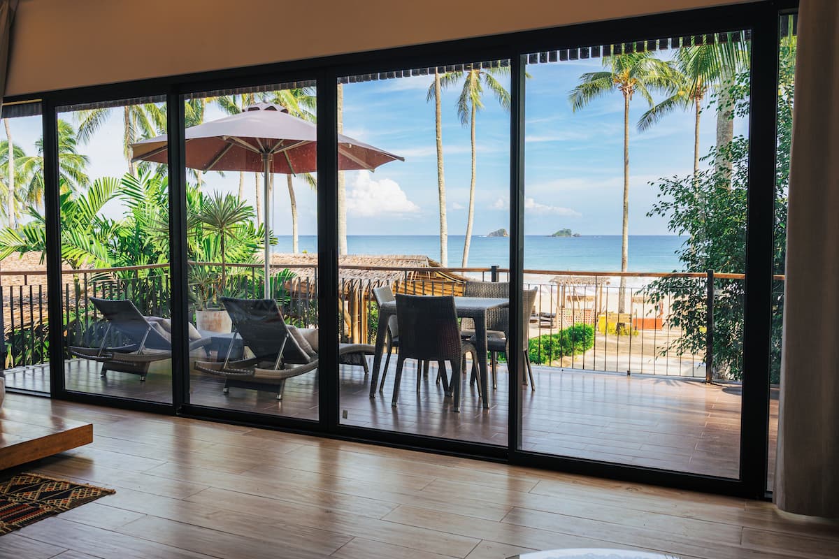 Une pièce dotée d’une grande porte-fenêtre coulissante donnant sur un balcon avec vue sur l’océan, ainsi que de mobilier d’extérieur et d’une table.
