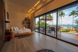 Une chambre avec une grande fenêtre, un lit, une table de chevet et une vue sur la plage.