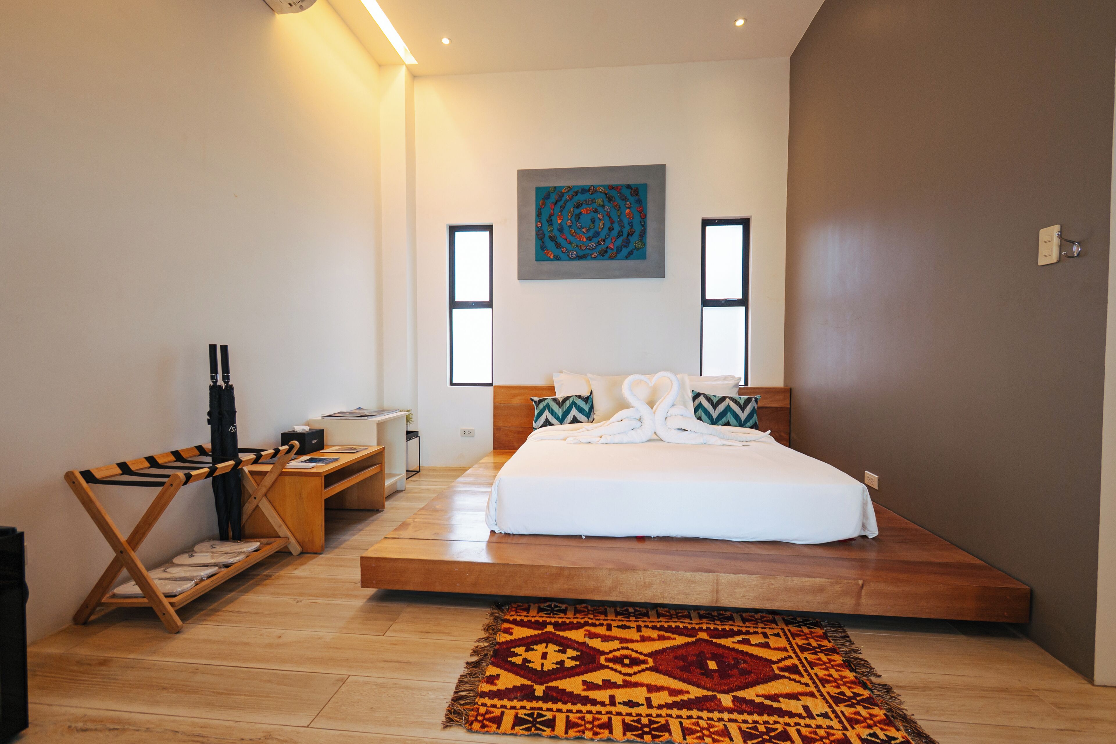 Quarto moderno com cama grande, piso de madeira e obra de arte original pendurada na parede.