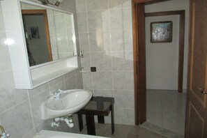 A bathroom with a white sink, a mirror, and a small wooden stool. - Double Room with Balcony 1 (Omis)