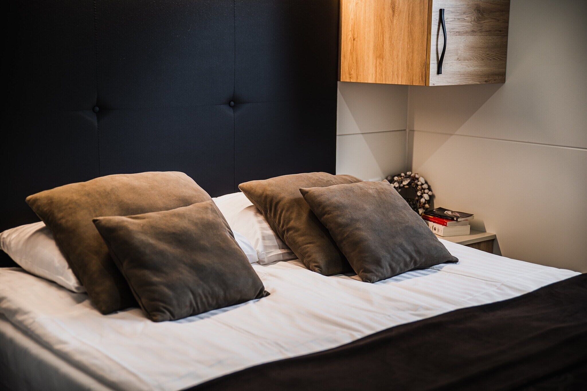 A neatly made bed with multiple pillows and a dark headboard.