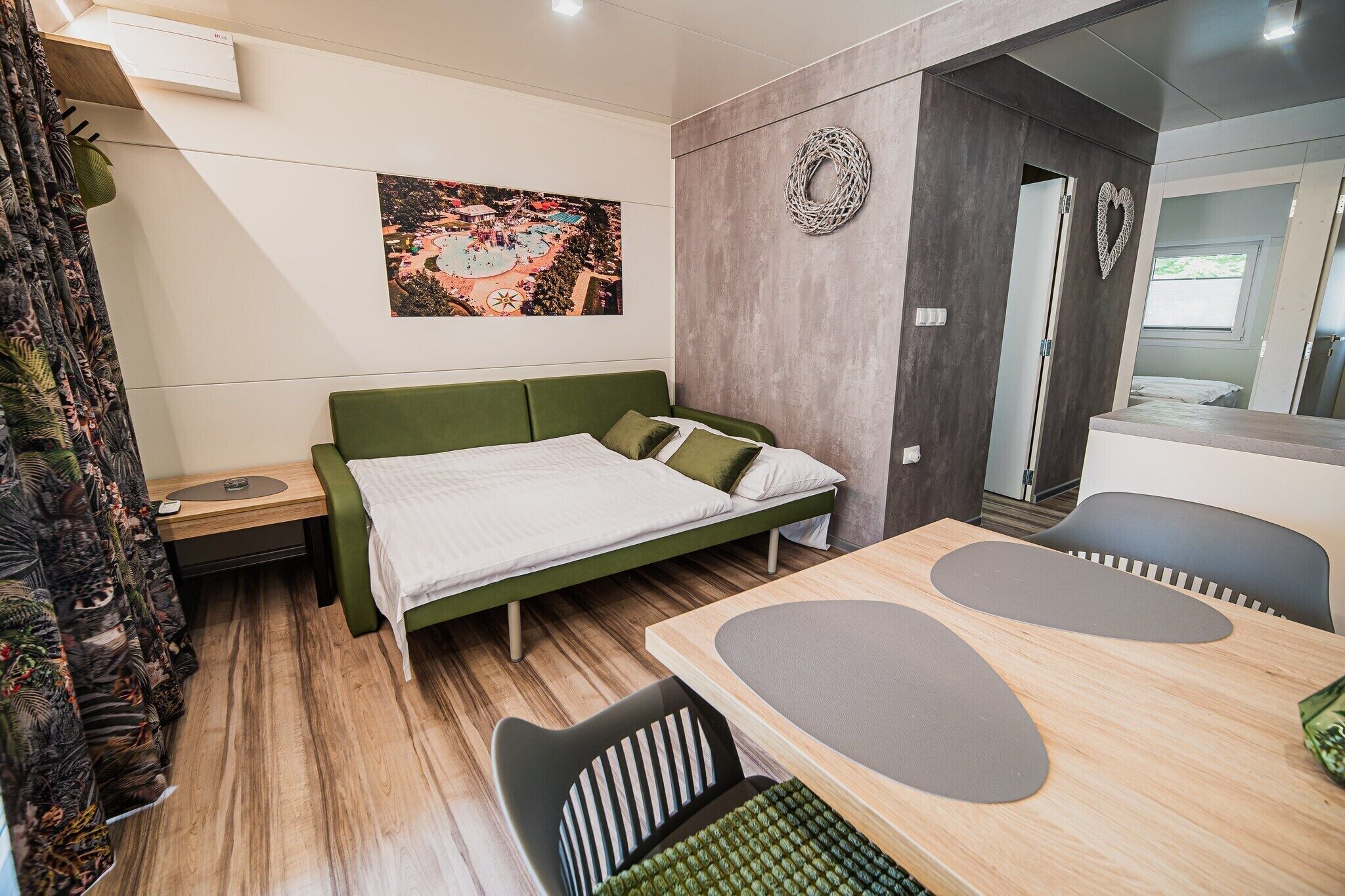 A modern bedroom with a bed, a desk, and a chair. There is a painting on the wall and a window.