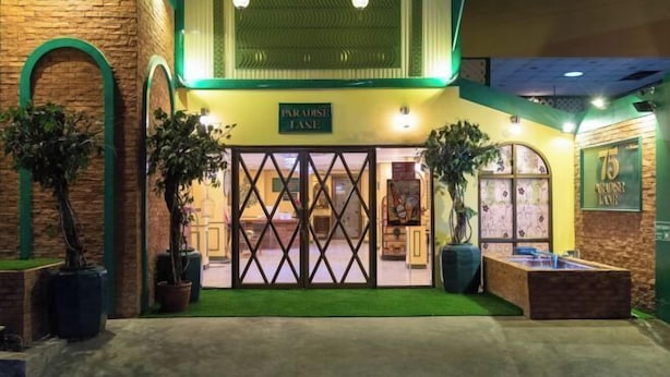 A hotel entrance with a sign reading "Paradise Lane," featuring a brick facade, green arches, and potted plants. - 75 Paradise Lane Managed by Loft Group (Bangkok)