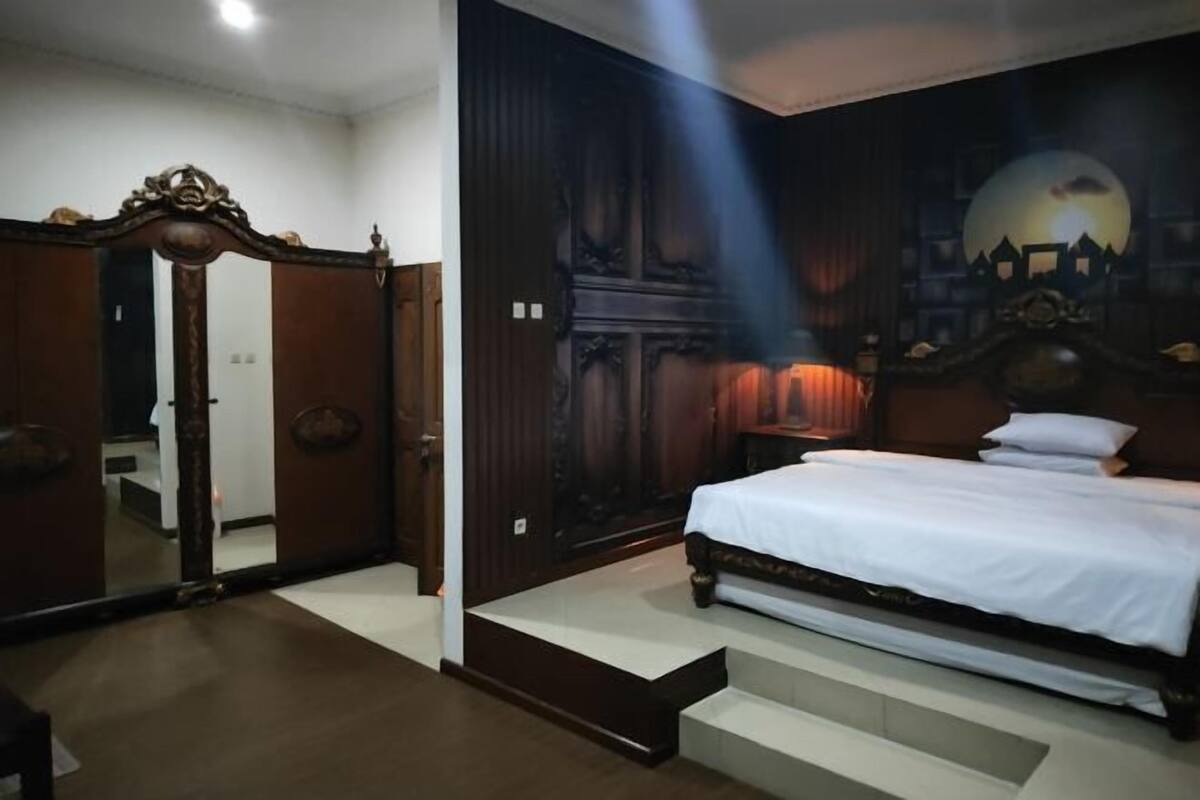 A bedroom with a bed, a mirror, a wardrobe, and a mural on the wall.