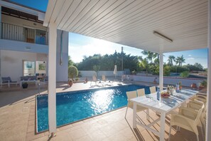 Un área junto a la piscina con sillas de descanso y una mesa con bebidas.