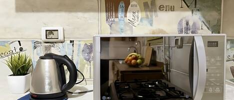 A kitchen with a built-in microwave and stove, a kettle, and a potted plant on the counter.