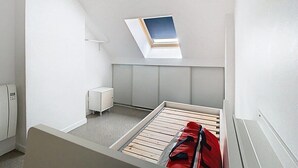 A small, bright room with a sloped ceiling, a skylight, a bed, and a small white cabinet. - The Little Rest - 40 m² Apartment center of Vitry (Vitry-en-Artois)