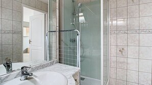 A bathroom with a marble sink, a glass shower enclosure, and tiled walls. - The Little Rest - 40 m² Apartment center of Vitry (Vitry-en-Artois)