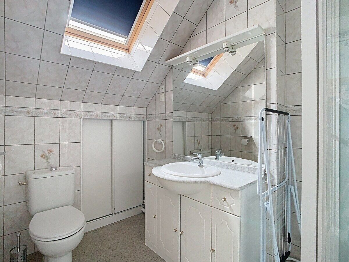 Un baño con tragaluz, dos lavamanos, inodoro y ducha.