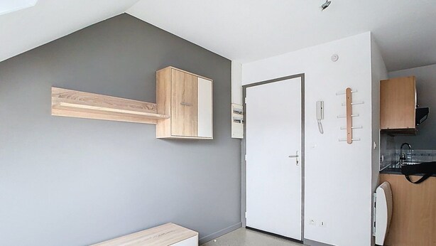 A modern, compact room with a built-in wardrobe, a small kitchenette, and a wooden bench. - The Little Rest - 40 m² Apartment center of Vitry (Vitry-en-Artois)