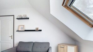 A room with a grey sofa, a wooden cabinet, and two shelves with framed pictures. - The Little Rest - 40 m² Apartment center of Vitry (Vitry-en-Artois)
