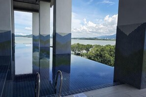 An infinity pool with a view of a lake and mountains, metal railings, and tiled walls. - BaySuites by Alawa Homes (Kota Kinabalu)
