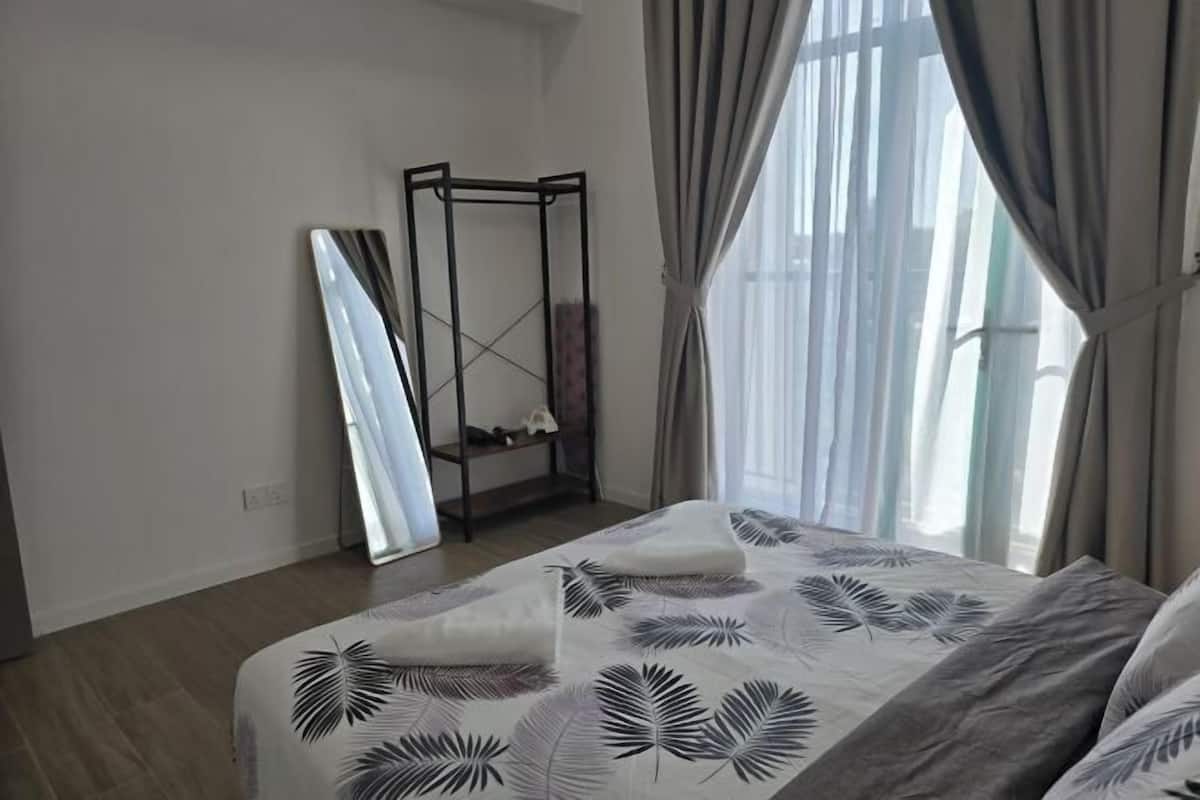 Une chambre à coucher avec un lit, un grand miroir et une fenêtre avec des rideaux.