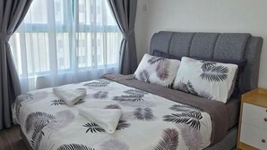 A neatly made bed with a leaf-patterned bedspread, a grey upholstered headboard, and a wooden nightstand with drawers. - BaySuites by Alawa Homes (Kota Kinabalu)