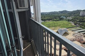 Un balcón con vista a un campo verde y edificios a lo lejos.