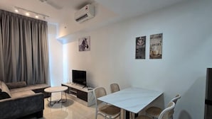 A modern living room with a sofa, TV, dining table, and chairs. - BaySuites by Alawa Homes (Kota Kinabalu)