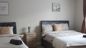 Ein Schlafzimmer mit zwei Betten, einem Nachttisch, einer Lampe und einem gerahmten Bild an der Wand.