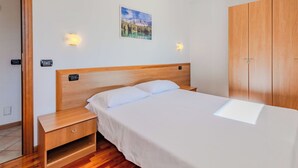 A bedroom with a wooden bed, a nightstand, a wardrobe, and a painting on the wall. - Beautiful apartment for 6 people with WIFI and TV (Pinzolo)