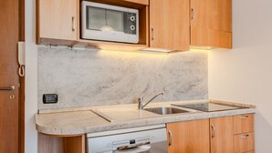 A compact kitchen with wooden cabinets, a built-in microwave, a stainless steel sink, and a dishwasher. - Beautiful apartment for 6 people with WIFI and TV (Pinzolo)