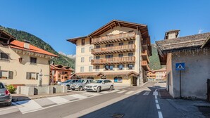 A multi-story hotel with balconies, parked cars, and a pedestrian crossing sign. - Beautiful apartment for 6 people with WIFI and TV (Pinzolo)