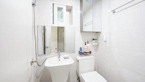 A small, clean bathroom with a white sink, toilet, and cabinet. - Ehwa Blossom (Seoul)