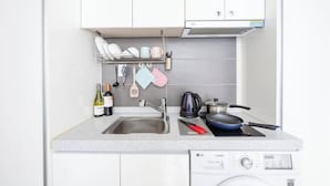 A compact kitchen with a sink, a stove, and a washing machine. - Ehwa Blossom (Seoul)