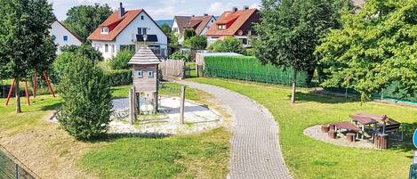 A residential area with a paved pathway, a small wooden structure, and a playground.