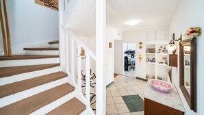 A staircase with brown steps and white railings, leading to a hallway with a kitchen area visible in the background. - Villa Vista Old Town - Four Bedroom House with Terrace and Sea View (Cavtat)