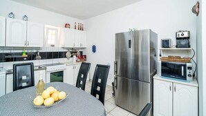 A compact kitchen with white cabinets, a stainless steel refrigerator, a microwave, and a dining table with chairs. - Villa Vista Old Town - Four Bedroom House with Terrace and Sea View (Cavtat)
