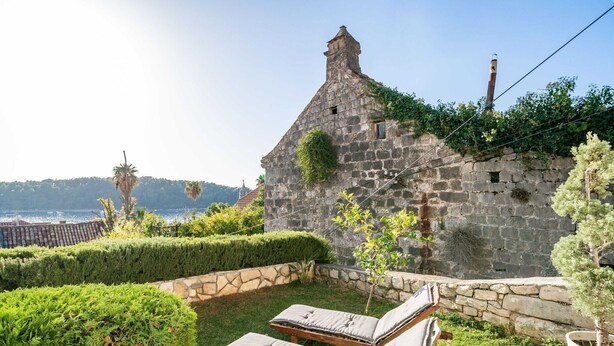A stone building with a sloped roof, a small window, and ivy growing on the wall. There are two wooden lounge chairs with cushions. - Villa Vista Old Town - Four Bedroom House with Terrace and Sea View (Cavtat)