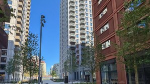 Una strada moderna in città, con palazzi alti, cielo sereno e marciapiede.