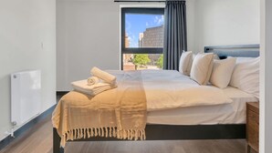 Una camera d'albergo moderna con un letto grande, vista sulla città e una finestra con tende.