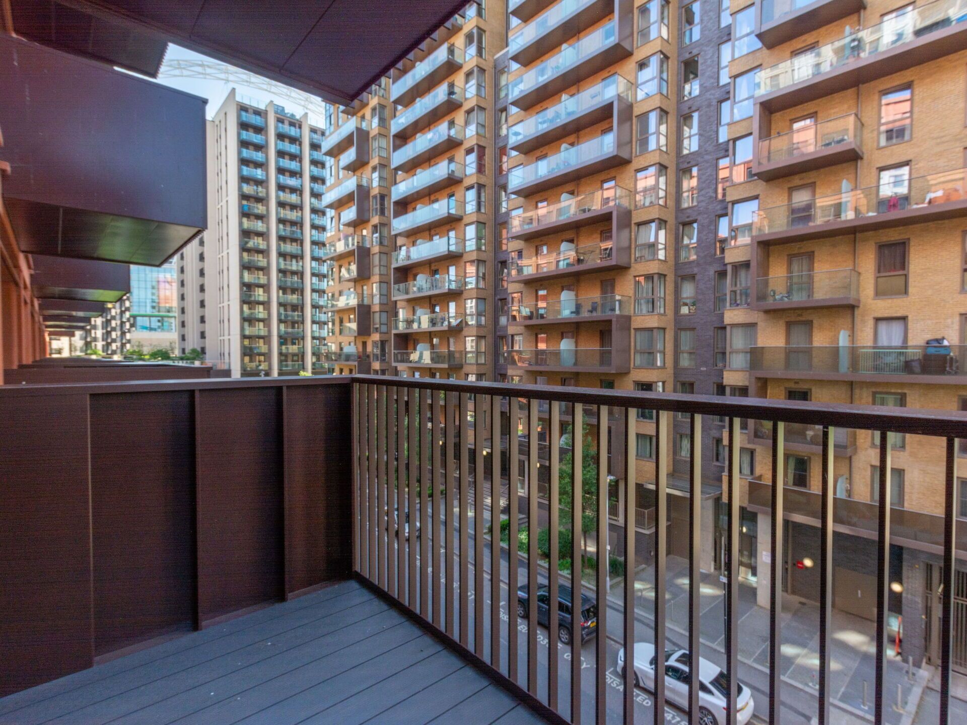 A modern apartment building with multiple balconies, a covered outdoor area, and a view of the street below.