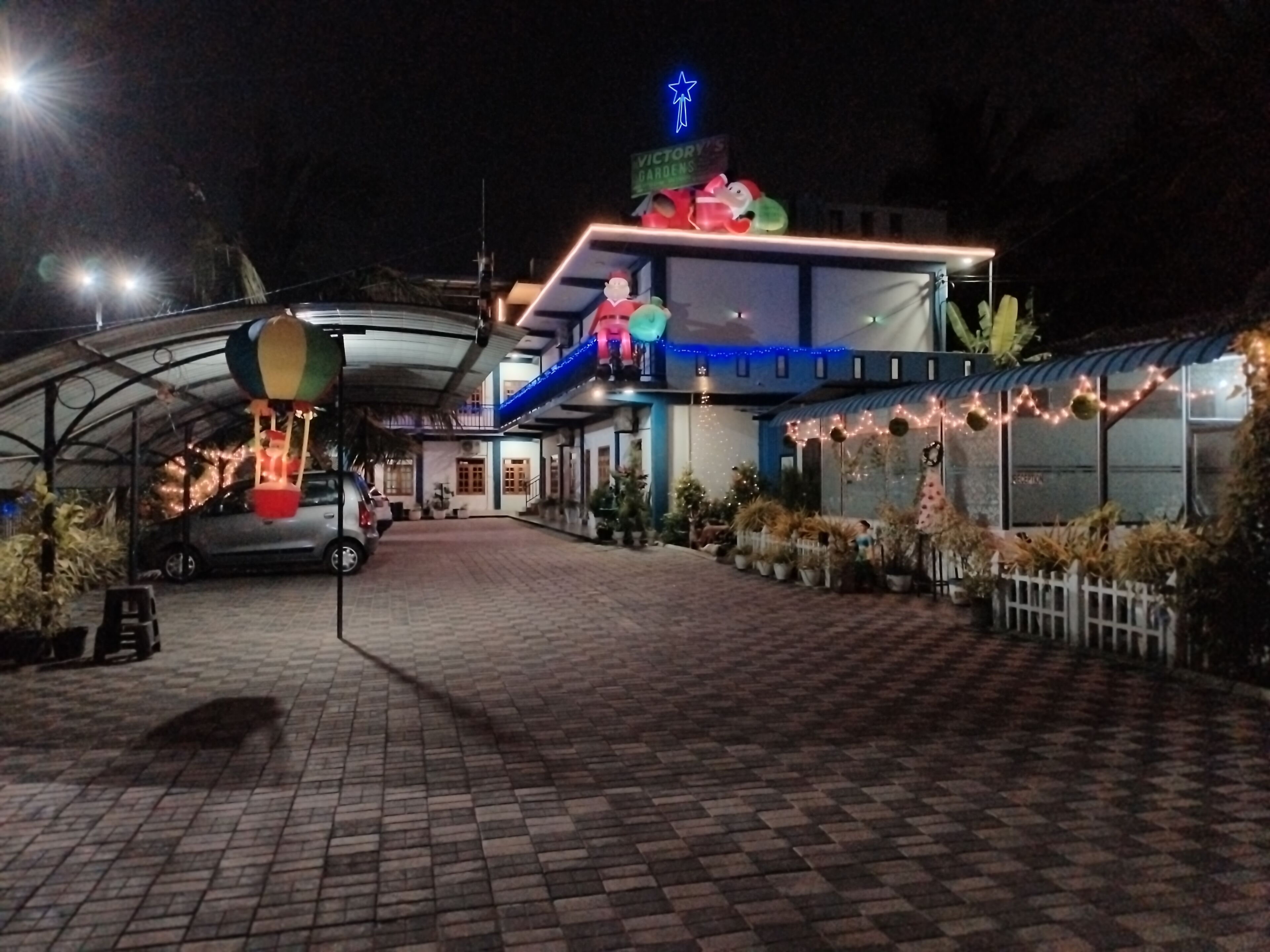 A building with a covered entrance, a sign for 'Victory Gardens,' and a blue star-shaped light on the roof.