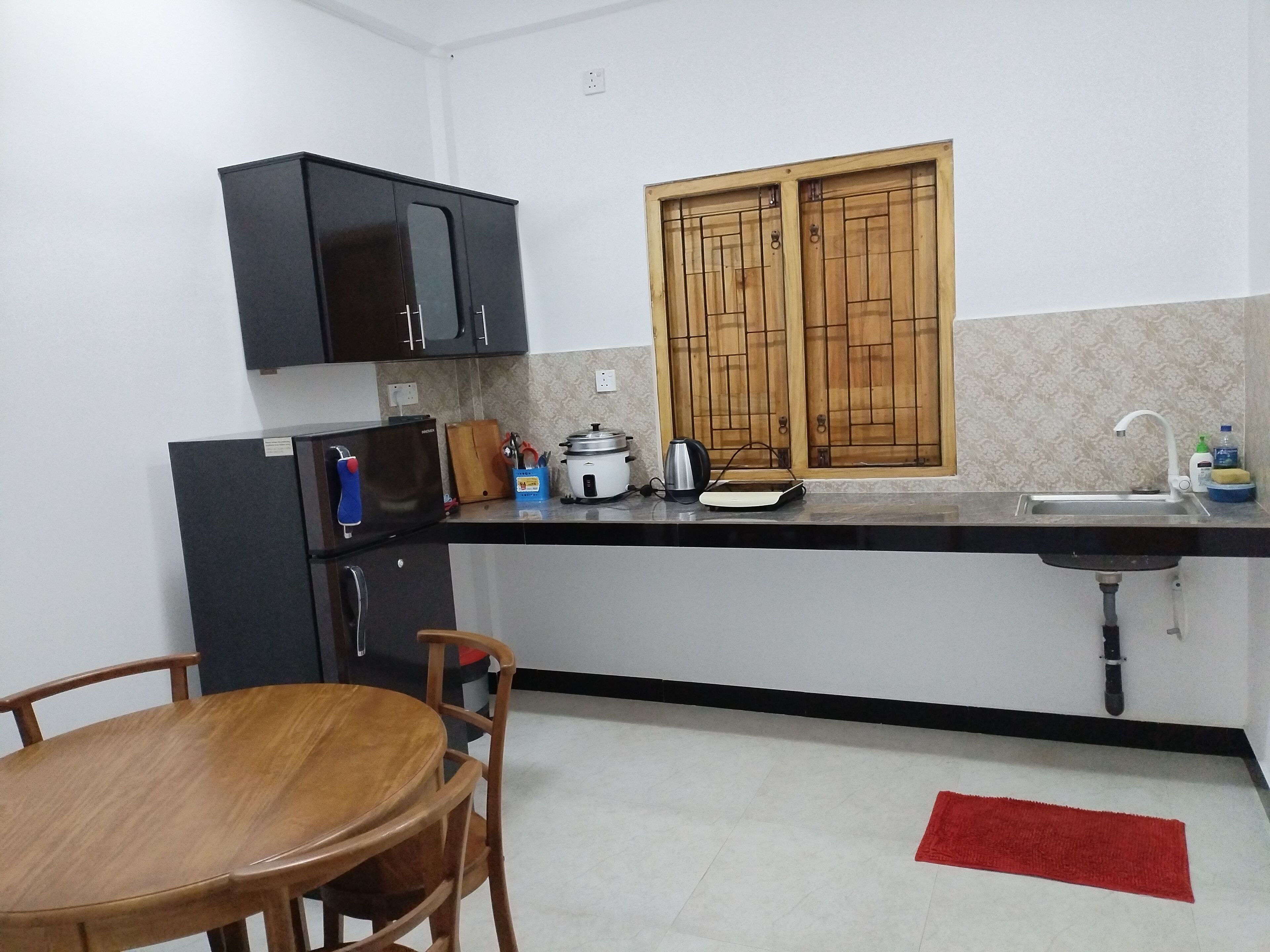 A compact kitchen with a sink, a stove, and a window with wooden shutters.
