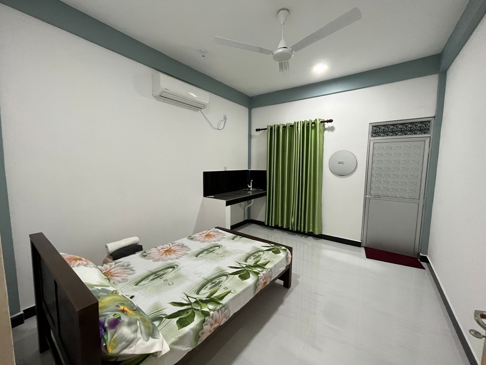 Una camera da letto con un letto, una televisione, un condizionatore, una ventola a soffitto e un armadio.