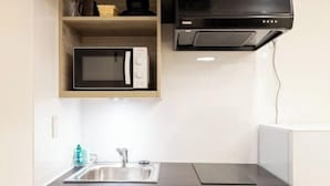A kitchen with a microwave, sink, and black range hood. - Retaw Hills Waseda (Tokyo)