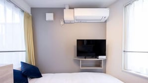 A hotel room with a bed, a TV, an air conditioning unit, and a window. - Retaw Hills Waseda (Tokyo)
