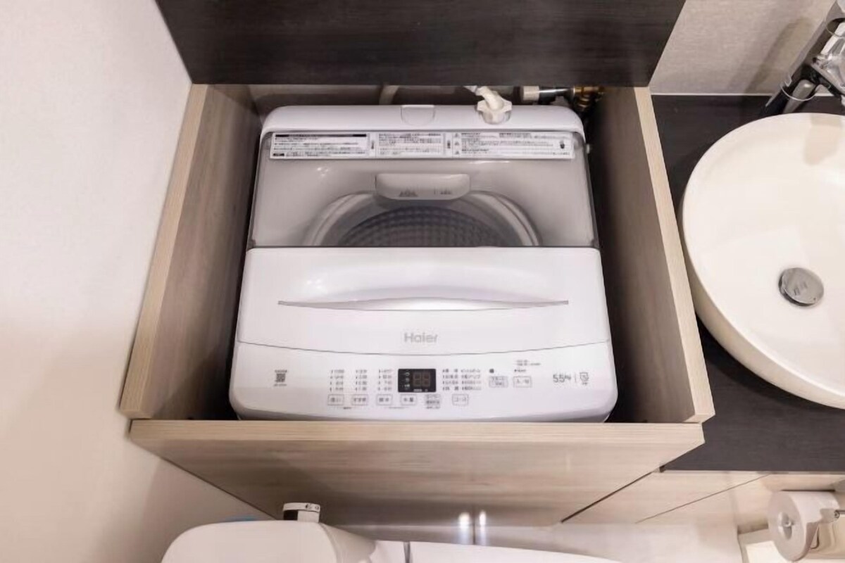 A compact washer and dryer unit in a wooden drawer, a sink, and a toilet.