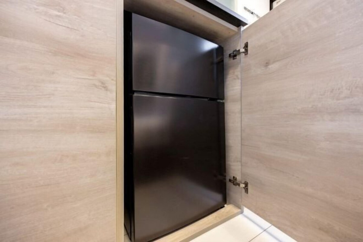 A kitchen with a black refrigerator and wooden cabinets.